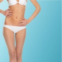 Thin woman in white bathing suit standing in front of a teal background